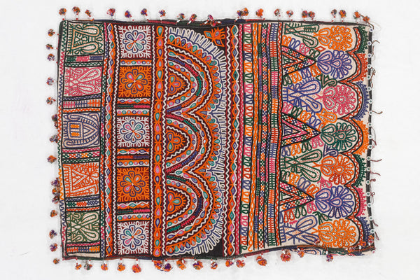 Colorful embroidered textile with intricate patterns and tassels on a white background