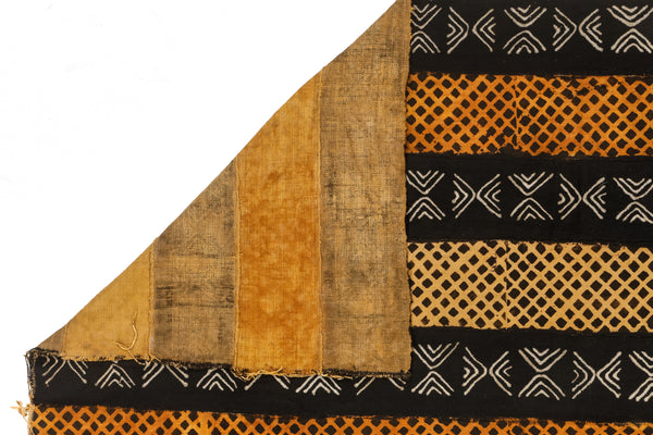 Close-up of a fabric with black, orange, and beige patterns on a white background